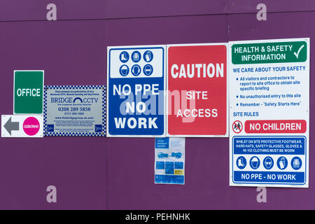 Una raccolta di indicazioni e di salute e gli avvisi di sicurezza su un bordo intorno a un edificio di costruzione del sito di sviluppo Foto Stock