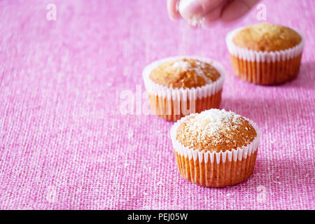 Fatti in casa muffin alla vaniglia con polvere di noce di cocco. Sfondo rosa. Copia dello spazio. Messa a fuoco selettiva. Buona mattina concetto. Foto Stock