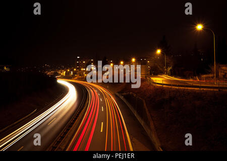 Una lunga esposizione colpo di un autostrada di notte, con veicolo sentieri di luce e di illuminazione pubblica in background Foto Stock