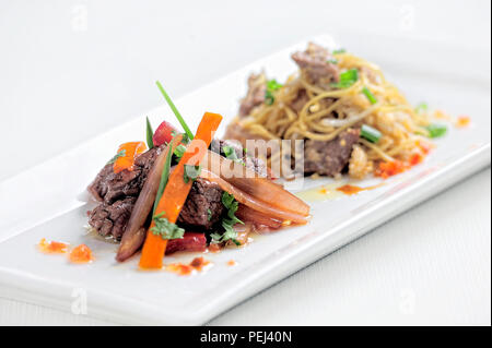 Piatto peruviano chiamato lomo saltado fatta di pomodoro, carne di manzo e cipolle miscelati con patatine fritte. Foto Stock