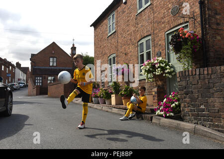 I ragazzi in Wolverhampton Wanderers FC kit replica a giocare a calcio al di fuori del luogo di nascita di lupi e Inghilterra leggenda calcistica di Billy Wright in Ironb Foto Stock