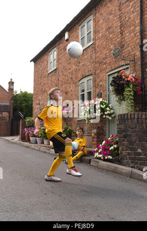 I ragazzi in Wolverhampton Wanderers FC kit replica a giocare a calcio al di fuori del luogo di nascita di lupi e Inghilterra leggenda calcistica di Billy Wright in Ironb Foto Stock