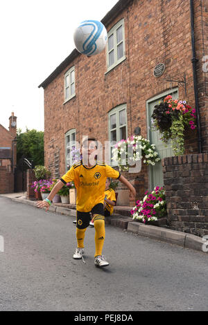 I ragazzi in Wolverhampton Wanderers FC kit replica a giocare a calcio al di fuori del luogo di nascita di lupi e Inghilterra leggenda calcistica di Billy Wright in Ironb Foto Stock