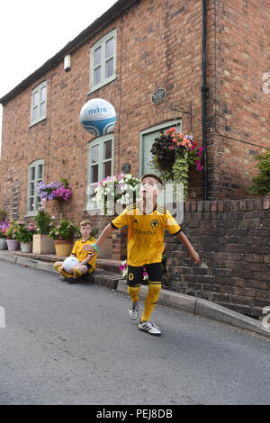 I ragazzi in Wolverhampton Wanderers FC kit replica a giocare a calcio al di fuori del luogo di nascita di lupi e Inghilterra leggenda calcistica di Billy Wright in Ironb Foto Stock