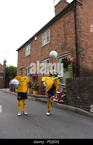 I ragazzi in Wolverhampton Wanderers FC kit replica a giocare a calcio al di fuori del luogo di nascita di lupi e Inghilterra leggenda calcistica di Billy Wright in Ironb Foto Stock