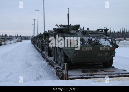 Strykers e altri veicoli di aspettare di essere guidato fuori le vetture del treno a Fort Wainwright, Alaska, Dicembre 9, 2015. Il ritorno dei veicoli segnala la fine del Pacifico Pathways missione in Giappone e Corea. Foto Stock