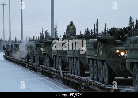 Strykers e altri veicoli di aspettare di essere guidato fuori le vetture del treno a Fort Wainwright, Alaska il 9 dicembre 2015. Il ritorno dei veicoli segnala la fine del Pacifico Pathways missione in Giappone e Corea. Foto Stock