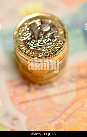 Pila di libbra di monete su British banconote Foto Stock