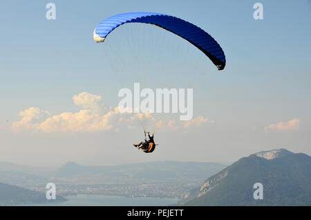 Parapendio vola nel cielo blu sullo sfondo di nuvole. Parapendio nel cielo in una giornata di sole. Extrem Sport e ricreazione. Foto Stock