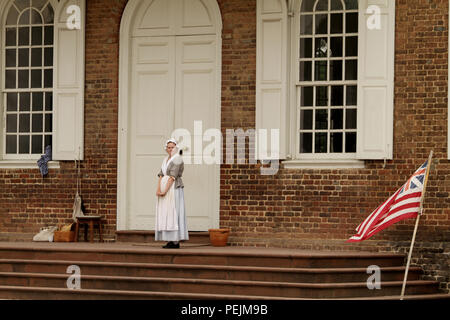 Donna reenactor a Colonial Williamsburg, Virginia, USA. La bandiera Grand Union, la prima bandiera nazionale degli Stati Uniti d'America. Foto Stock