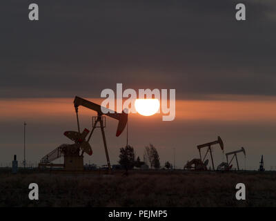 In North Texas vicino a Wichita Falls un gas naturale rig imposta nella parte anteriore delle turbine eoliche. Contrasto di energia rinnovabile con il vecchio combustibile fossile. Foto Stock