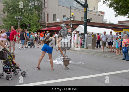 ASHEVILLE, NC, Stati Uniti d'America - 27 luglio 2013: una donna suggerimenti una statua vivente attore raffigurante un vecchio, batterista presso l'ultimo bele Chere Festival in 2013 Foto Stock