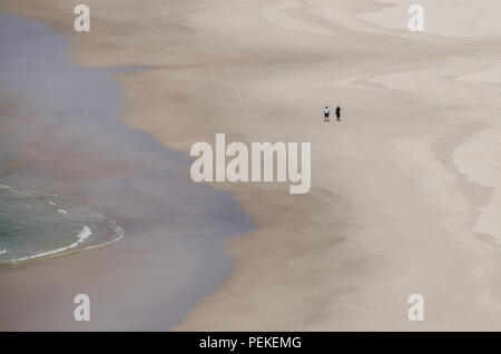 Due persone a piedi lungo il bordo delle acque sulla spiaggia vuota, Tallow Beach, Byron Bay, Nuovo Galles del Sud, Australia. Le coppie pacifica solitudine sulla spiaggia solitaria . Foto Stock