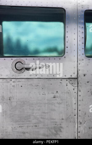 La maniglia della porta e i rivetti nella fusoliera di un velivolo vintage verde con oblò trasparente Foto Stock