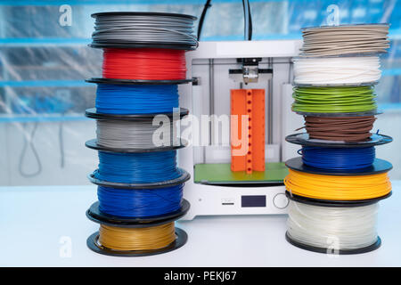 ABS e PLA filament accanto alla stampante 3D. Bobine di plastica Foto Stock