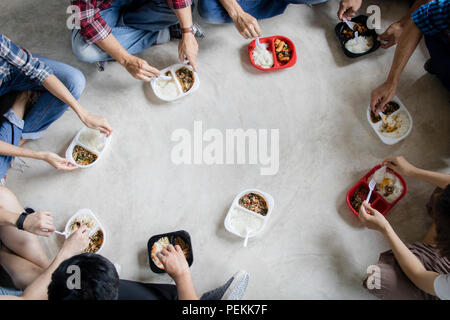 Vista superiore del lavoro di squadra e il team concetto di gruppo, Tailandese popoli asiatici seduto sul pavimento e godendo di mangiare fast food che acquisti dal negozio Foto Stock