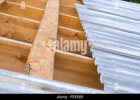 Il tetto di ferro sul tetto incompiuto di una gabbia in legno Foto Stock