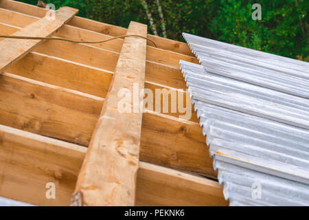 Il tetto di ferro sul tetto incompiuto di una gabbia in legno Foto Stock