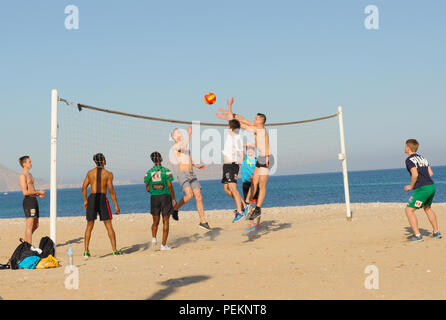 Giovani uomini giocando a pallavolo sulla spiaggia di spagnolo