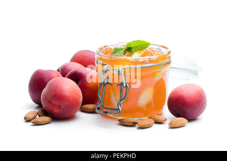 Red marmellata di albicocche con mandorle in un chiaro il vasetto di vetro isolato su bianco Foto Stock