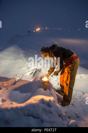 Airman 1. Classe Anthony Cooper, un 354Ingegnere Civile Squadron impianti elettrici artigiano, opere in un acquazzone di neve per cambiare le luci sulla airfield il 4 dicembre a Eielson Air Force Base in Alaska. Alcune operazioni devono essere presi da aviosuperficie tecnici di illuminazione per garantire l'illuminazione è funzionale 24/7 consentendo una aviosuperficie funzionale per le missioni che potrebbe variare attraverso gli Stati Uniti Pacific Air Forces area di operazioni. (U.S. Air Force photo by Staff Sgt. Shawn nichel/rilasciato) Foto Stock