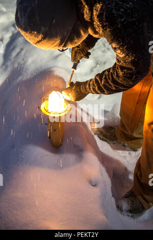 Airman 1. Classe Anthony Cooper, un 354Ingegnere Civile Squadron impianti elettrici artigiano, opere in un acquazzone di neve per cambiare le luci sulla airfield il 4 dicembre a Eielson Air Force Base in Alaska. Alcune operazioni devono essere presi da aviosuperficie tecnici di illuminazione per garantire l'illuminazione è funzionale 24/7 consentendo una aviosuperficie funzionale per le missioni che potrebbe variare attraverso gli Stati Uniti Pacific Air Forces area di operazioni. (U.S. Air Force photo by Staff Sgt. Shawn nichel/rilasciato) Foto Stock