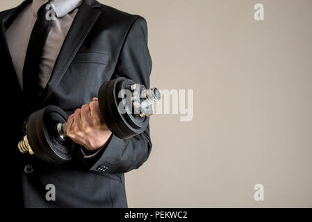 Un imprenditore facendo dumbbell curl bicipiti indossando un abito formale. Concettuale del business di forza. Foto Stock