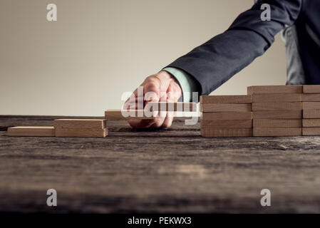 Immagine concettuale di risoluzione dei problemi aziendali e il successo con un imprenditore formando un ponte di costruzione in legno di blocchi in un gap di un set o passi, per Foto Stock