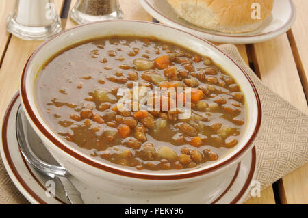 Una ciotola di sano zuppa di lenticchie con un rotolo di cena Foto Stock