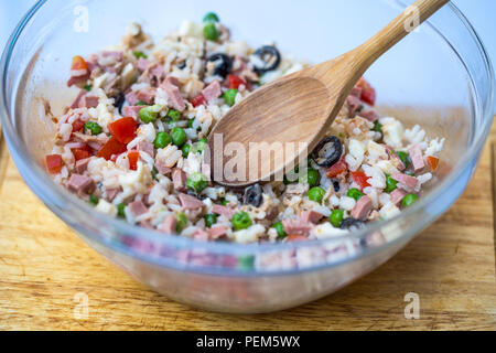 Italiano insalata di riso o riso freddo in un involucro di vetro con cucchiaio ligneo su di un tagliere con sfondo bianco. Foto Stock