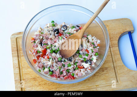 Italiano insalata di riso o riso freddo in un involucro di vetro con cucchiaio ligneo su di un tagliere con sfondo bianco. Foto Stock