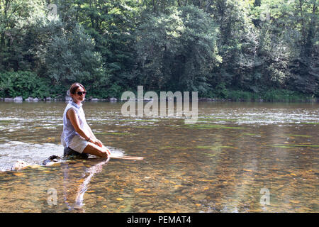 Bella donna il raffreddamento le gambe in un fiume, Onda di Calore e calda estate, Francia. Foto Stock