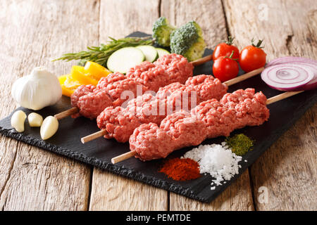 Lyulya, kofta, kebab kofte da materie la carne di suolo su spiedini con spezie, erbe e verdure vicino sul tavolo orizzontale. Foto Stock