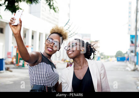 Due lieti imprenditrici tenendo selfie da smart phone al di fuori Foto Stock