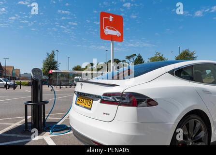 Auto elettrica inserita in un punto di carica. Il veicolo elettrico collegato ad un condotto di carica nel West Sussex, in Inghilterra, Regno Unito. Foto Stock