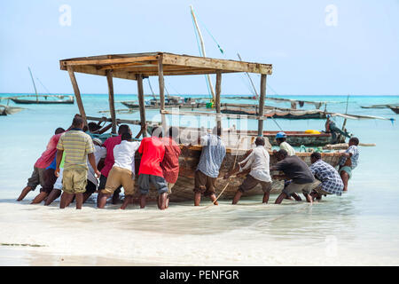 Stone Town, Zanzibar, 24 maggio - 2015: Uomini spingendo barca da pesca in mare. Foto Stock