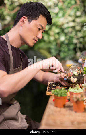 Giovane uomo che lavora nel negozio di vegetali Foto Stock