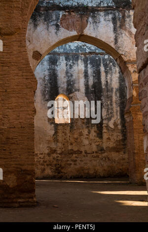 Vista dall'interno di un edificio su i dettagli delle pareti in rovina di necropoli Chellah, Rabat, Marocco. Pareti a spiovente con un portale e finestra, bot Foto Stock