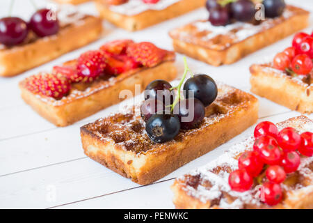 Waffles fatti in casa con frutti di bosco in estate su un tavolo luminoso. Messa a fuoco selettiva. Foto Stock