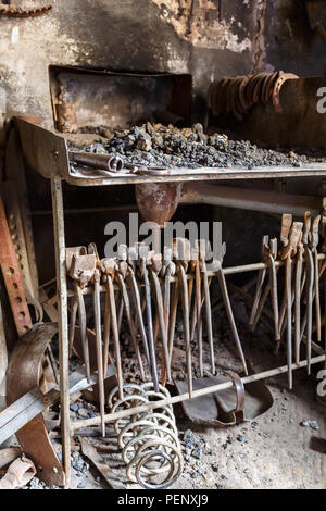 Forge con un focolare e vecchie pinze e strumenti in un workshop Foto Stock