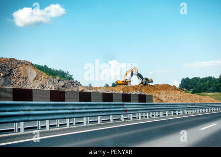 Due pesanti, il giallo e il nero escavatori sul sito in costruzione lo spostamento delle rocce e del suolo, Autostrada, strada in costruzione, i bracci sono attraversati Foto Stock