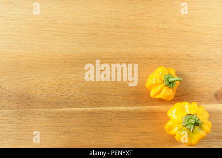 Composizione del giallo fresco Scotch Bonnet il peperoncino su una tavola di legno con spazio di copia Foto Stock