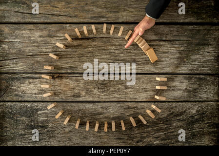 Imprenditore arrestando la caduta dei dominos collocato in un cerchio con la sua mano. Conceptual di crisi e di gestione dei problemi. Foto Stock