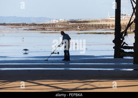 Hastings, East Sussex, Regno Unito. 17 Ago, 2018. Regno Unito: Meteo calda e soleggiata mattina in Hastings, East Sussex con un sacco di gente fuori sulla spiaggia. Le temperature sono dovrebbe superare 21°C. Un detectorist perlustra la spiaggia in cerca di tesori perduti con un rivelatore di metallo mentre la marea è fuori sotto il molo. © Paul Lawrenson 2018, Photo credit: Paolo Lawrenson / Alamy Live News Foto Stock