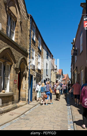 Persone turisti visitatori a piedi nel centro della città in estate Church Street Whitby North Yorkshire Inghilterra Regno Unito GB Gran Bretagna Foto Stock