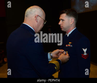 Adm posteriore. Richard Gromlich, Comandante della Guardia Costiera XIII quartiere, presenta Petty Officer 2a classe Darren Harrity, una sopravvivenza di aviazione tecnico assegnato alla guardia costiera Stazione aria North Bend, con la Coast Guard medaglia a uno screening dei migliori ore a Seattle, 20 gennaio, 2016. Harrity nuotato più di 1.700 metri per il soccorso di quattro pescatore vicino a Capo Blanco, Ore., nel luglio 2015. (U.S. Coast Guard foto di Sottufficiali di prima classe George Degener) Foto Stock