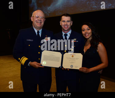 Petty Officer 2a classe Darren Harrity, una sopravvivenza di aviazione tecnico assegnato alla guardia costiera Stazione aria North Bend, Ore., e il suo fidanzato, Chelsey Larsen, cavalletto posteriore con ADM. Richard Gromlich, Comandante della Guardia Costiera XIII quartiere, dopo aver presentato Gromlich Harrity con la Coast Guard medaglia prima uno screening dei migliori ore a Seattle, 20 gennaio, 2016. La Guardia Costiera della medaglia viene assegnato a tutti i membri delle forze armate che, pur servendo in qualsiasi capacità con la Coast Guard, distingue se stesso da un eroismo che non coinvolgono il conflitto reale con un nemico. (U.S. Coast Guard ph Foto Stock