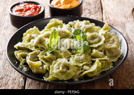 Deliziosa verde di spinaci cappelletti, ravioli, tortellini con parmigiano e basilico, salse close-up sul tavolo orizzontale. Foto Stock