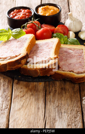 Cibo francese: Terrina pate in una brioche con spezie, aglio servita con verdure e salse close-up sul piano verticale. Foto Stock