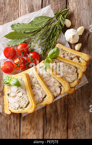 Terrina di pollo, gelatina, aspic con brioche servita con erbe e verdure vicino sul tavolo. Verticale in alto vista da sopra Foto Stock